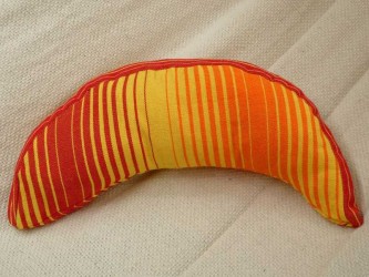 Coussin sur un hamac en tissu à rayures rouges et jaunes, sur un tissu blanc