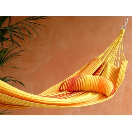 Coussin sur un hamac en tissu à rayures rouges et jaunes sur une terrasse tropicale