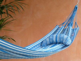 Coussin cervical en tissu polygonal turquoise et blanc, en forme de demi-lune, sur une terrasse