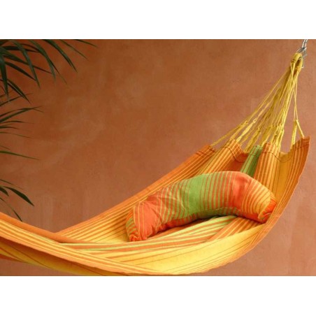 Coussin sur un hamac en tissu à rayures verts et oranges sur une terrasse tropicale