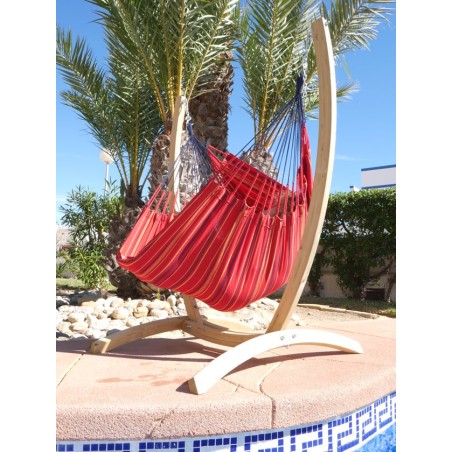 Hamac chaise rouge et support en bois devant une piscine