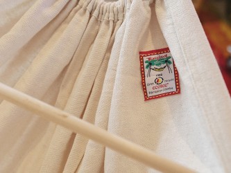 Hamac bébé El Cayuco écru, détail de l'angle, en se concentrant sur le label de la marque Tropical Hamac