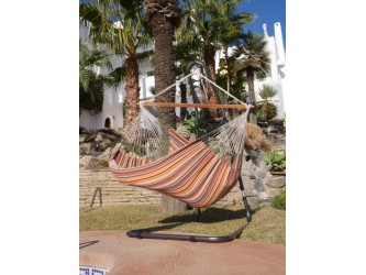 Une fille se balançant dans un chaise hamac XXL multicolore au bord d'une piscine