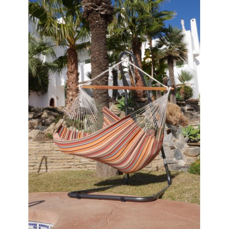 Une fille se balançant dans un chaise hamac XXL multicolore au bord d'une piscine