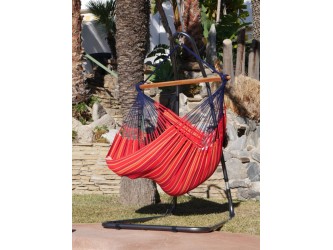 Une fille se balançant dans un chaise hamac XXL rouge multicolore au bord d'une piscine