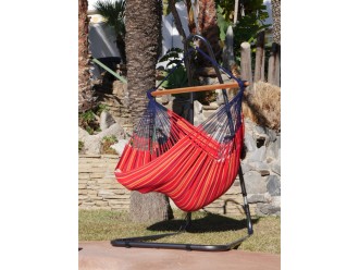 Une fille se balançant dans un chaise hamac XXL rouge multicolore au bord d'une piscine