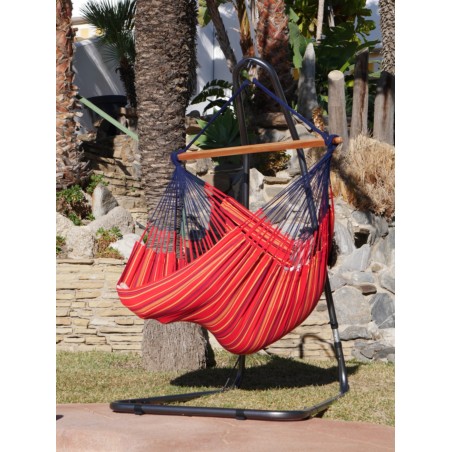 Une fille se balançant dans un chaise hamac XXL rouge multicolore au bord d'une piscine