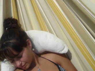 Femme détendue dans un hamac avec coussin écru, moment de relaxation