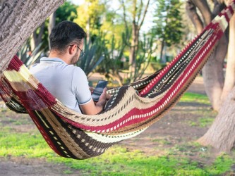 Homme dans un hamac mexicain XXL multicolore  dans le jardin