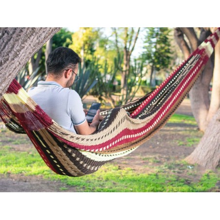 Homme dans un hamac mexicain XXL multicolore  dans le jardin