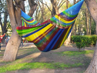 Homme dans un hamac mexicain XXL multicolore  dans le jardin