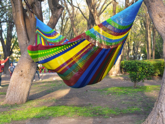 Homme dans un hamac mexicain XXL multicolore dans le jardin Homme dans un hamac mexicain XXL multicolore dans le jardin