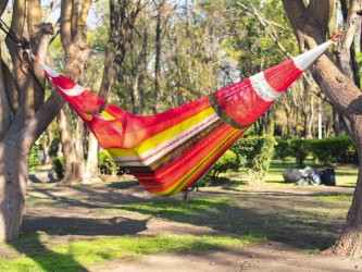 Homme dans un hamac mexicain XXL multicolore  dans le jardin