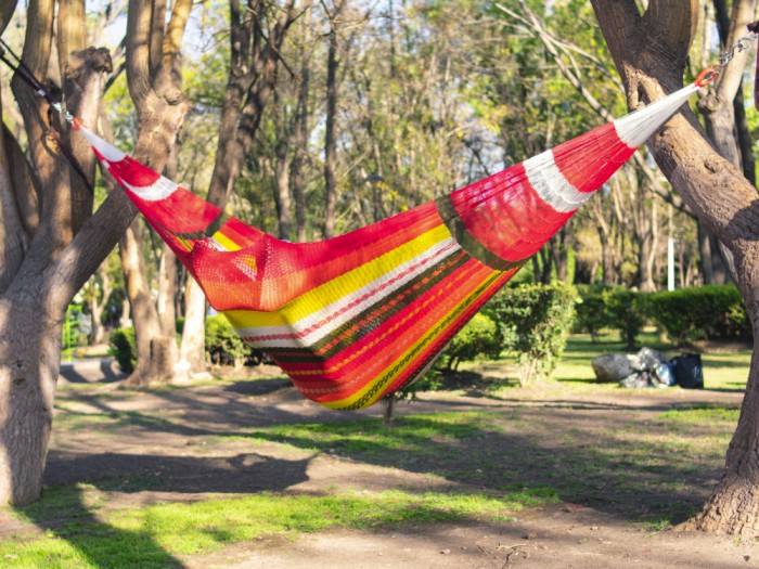 Homme dans un hamac mexicain XXL multicolore dans le jardin Homme dans un hamac mexicain XXL multicolore dans le jardin