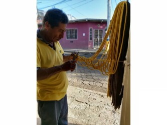 Artisan nicaraguayen fabriquant un hamac jaune dans l'atelier