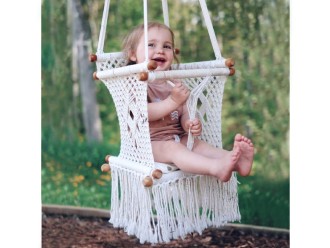 Bébé heureux dans hamac macramé écru suspendu à l’extérieur