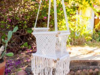 Hamac bébé macramé écru suspendu dans un jardin lumineux, ambiance naturelle