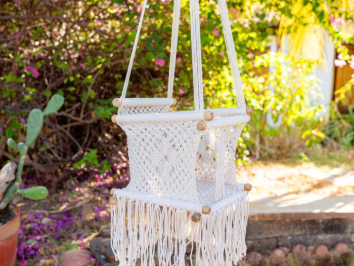 Hamac bébé macramé écru suspendu dans un jardin lumineux, ambiance naturelle
