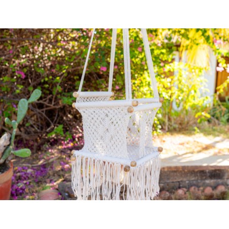 Hamac bébé macramé écru suspendu dans un jardin lumineux, ambiance naturelle
