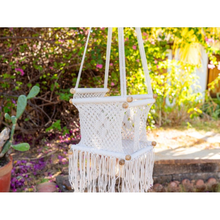 Hamac bébé macramé écru suspendu dans un jardin lumineux, ambiance naturelle