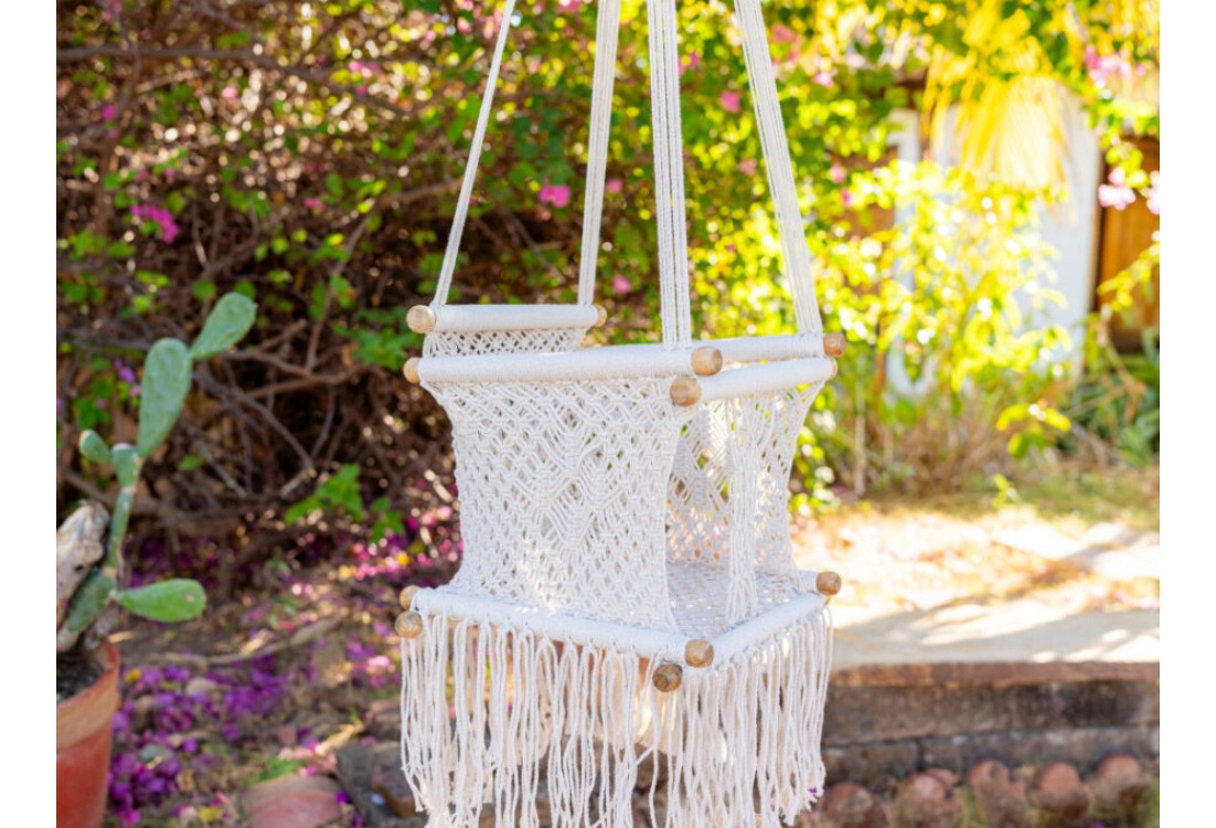 Hamac bébé macramé écru suspendu dans un jardin lumineux, ambiance naturelle