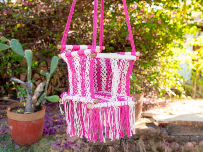Hamac suspendue pour bébé en coton macramé rose, installée en extérieur dans un cadre naturel
