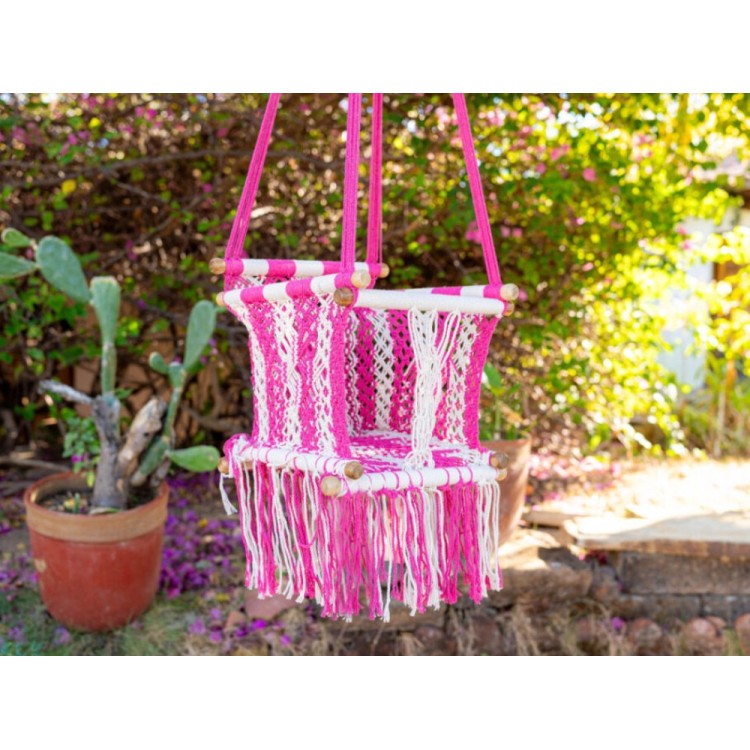 Hamac suspendue pour bébé en coton macramé rose, installée en extérieur dans un cadre naturel