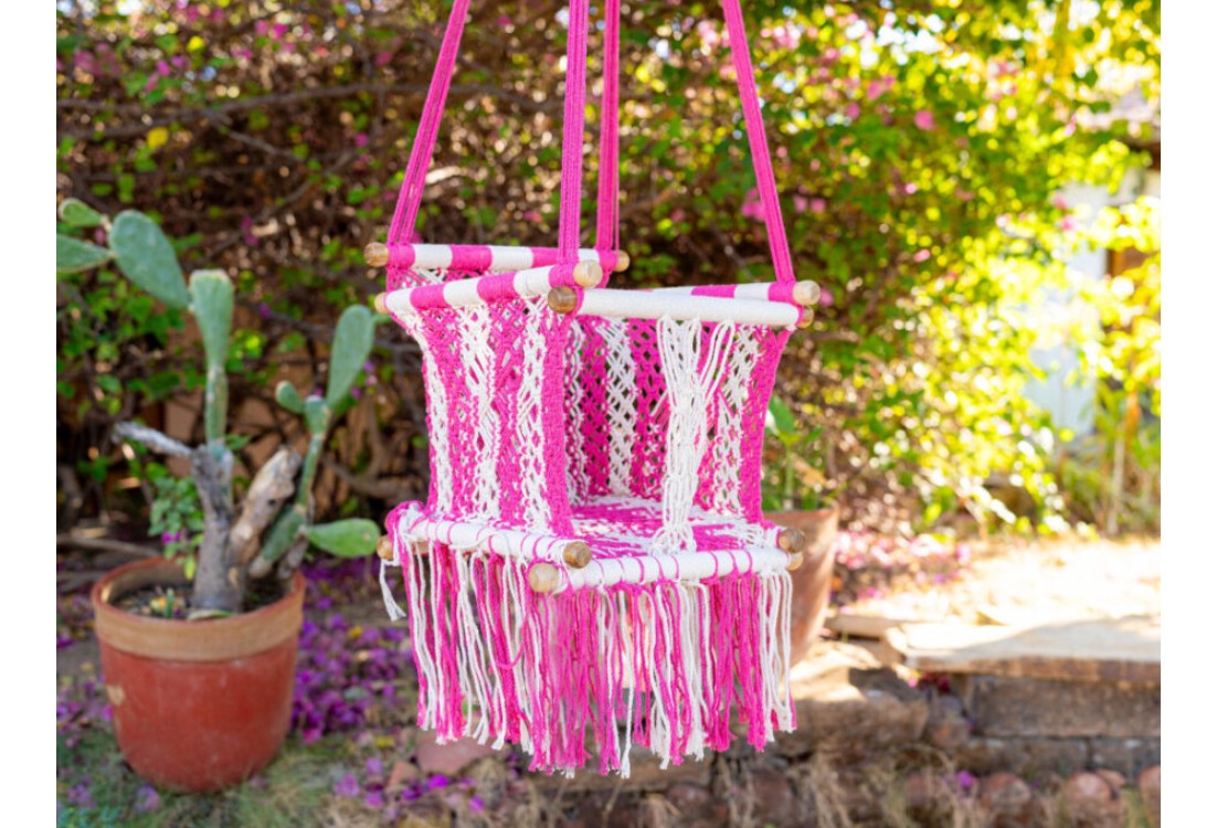 Hamac suspendue pour bébé en coton macramé rose, installée en extérieur dans un cadre naturel