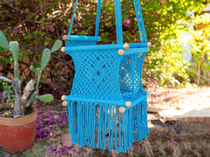 Hamac bébé suspendu en macramé bleu avec coussins colorés, idéal pour le jardin ou l'intérieur