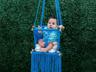 Bébé s'amuse dans un hamac suspendu en macramé bleu, sûr et confortable pour une utilisation en extérieur