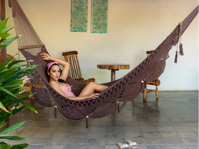 Femme allongée dans un hamac chocolat à barres en bois, intérieur colonial