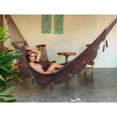 Femme allongée dans un hamac chocolat à barres en bois, intérieur colonial