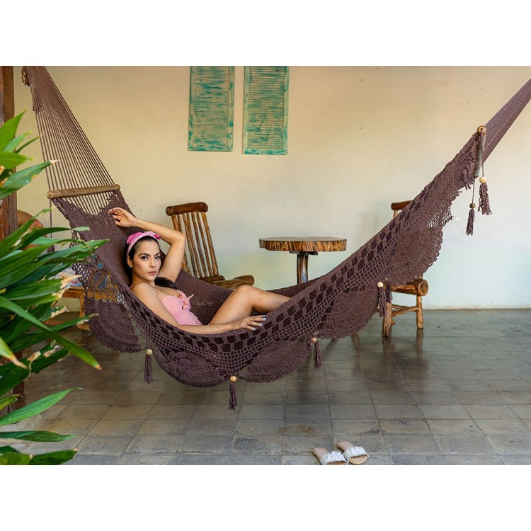 Femme allongée dans un hamac chocolat à barres en bois, intérieur colonial