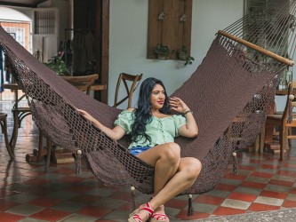 Femme assis dans un hamac à barres en coton chocolat