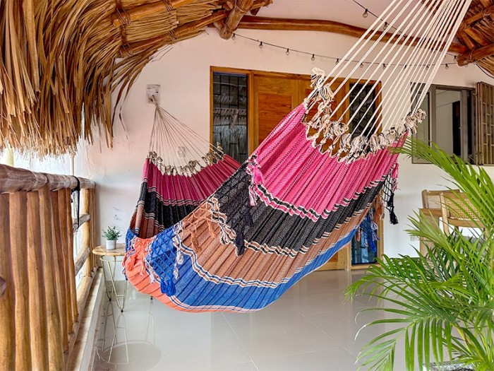 Hamac vénézuélien aux couleurs vives (rose, noir, bleu) suspendu à l'intérieur