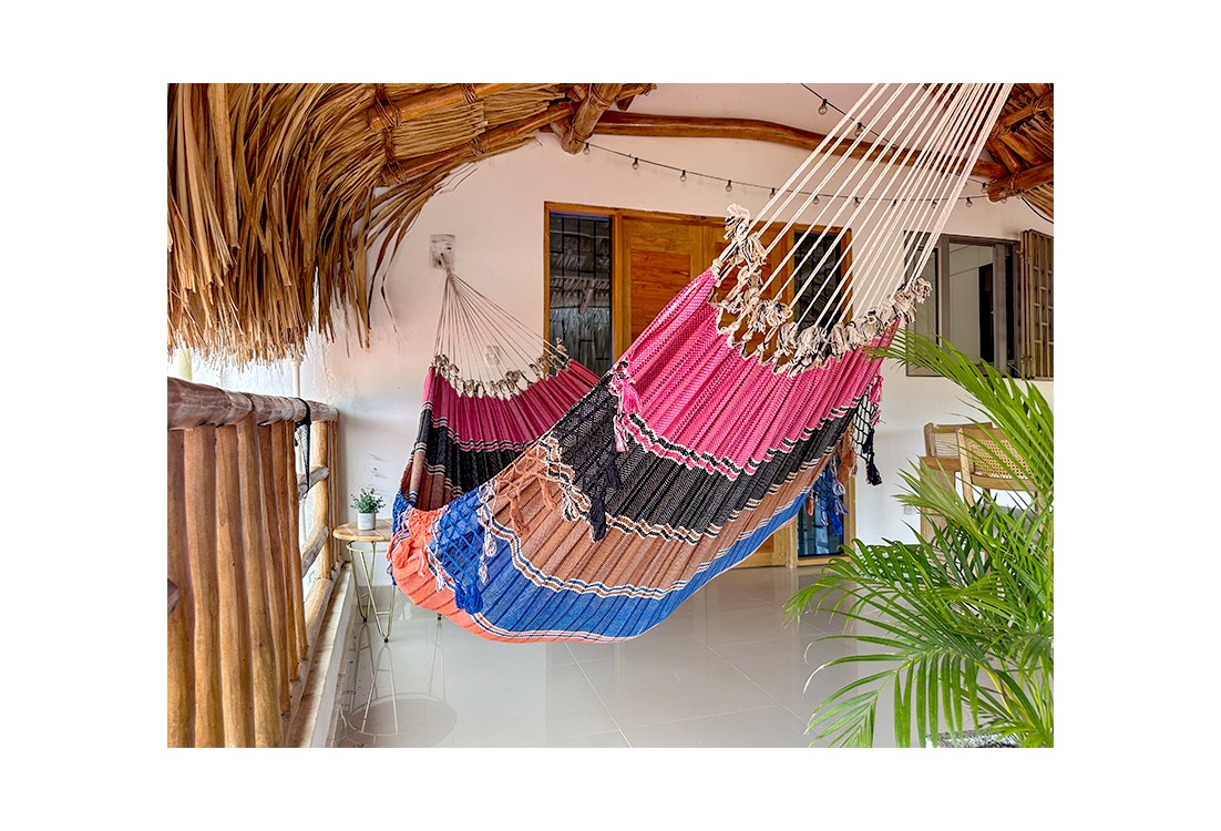 Hamac vénézuélien aux couleurs vives (rose, noir, bleu) suspendu à l'intérieur