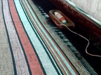 Détail des toiles en cours de fabrication sur métier à tisser traditionnel, montrant la richesse des couleurs