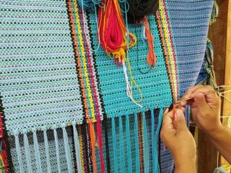 Artisane vénézuélienne en train de tisser un hamac à la main avec des fils colorés