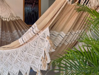 Hamac en coton tissé avec franges décoratives, suspendu entre palmiers