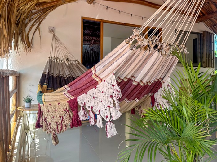 Hamac vénézuélien bordeaux et beige avec franges artisanales, suspendu en terrasse Hamac vénézuélien bordeaux et beige avec franges artisanales, suspendu en terrasse