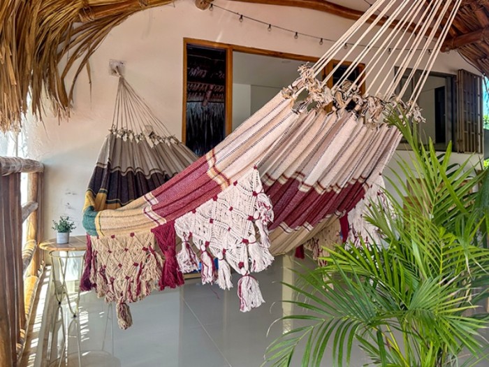 Hamac vénézuélien bordeaux et beige avec franges artisanales, suspendu en terrasse