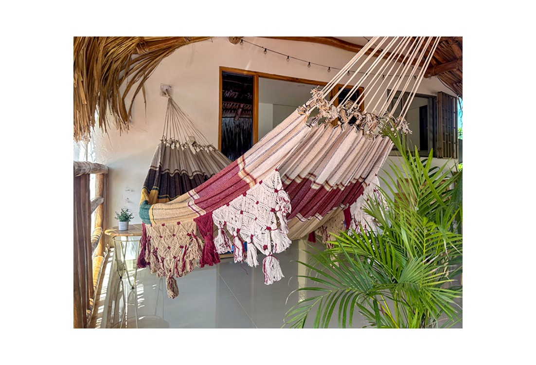 Hamac vénézuélien bordeaux et beige avec franges artisanales, suspendu en terrasse