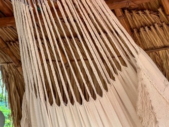 Vue rapprochée du tissu de couleur écru ou beige du hamac colombien, avec le détail du motif diamants tissé sur les bords