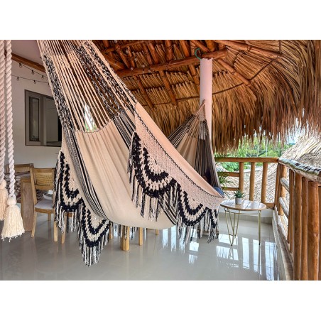 Hamac colombien XL sur un porche avec toit en palmier, montrant son contraste de couleurs clair et foncé et son motif distinctif