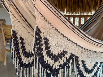 Détail du tissage artisanal du hamac colombien, soulignant le motif tribal foncé complexe sur fond clair et les franges