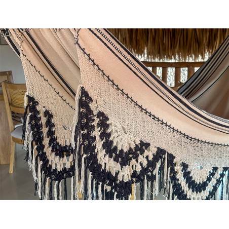 Détail du tissage artisanal du hamac colombien, soulignant le motif tribal foncé complexe sur fond clair et les franges