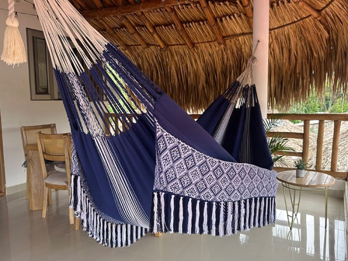 Hamac colombien taille L en tissu bleu avec des motifs blancs, suspendu sous un toit de chaume