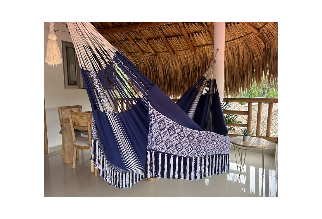 Hamac colombien taille L en tissu bleu avec des motifs blancs, suspendu sous un toit de chaume