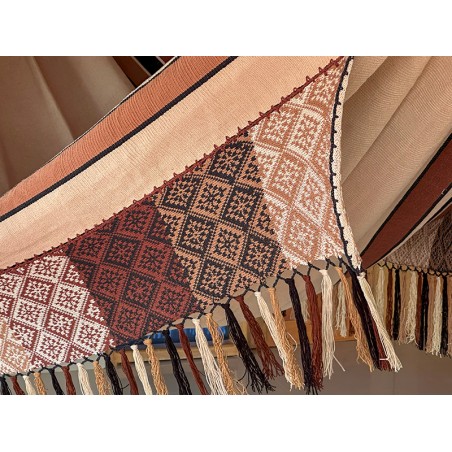 Gros plan du motif artisanal détaillé et des franges aux extrémités du hamac, dans une palette harmonieuse de couleurs terre