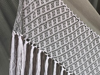 Détail rapproché du motif géométrique et de la texture du tissage d'un hamac colombien dans des tons gris-vert doux et blanc